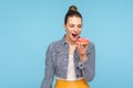 Delighted beautiful woman with hair bun looking at delicious doughnut with desire, keeping her mouth opened Royalty Free Stock Photo