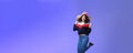 Delighted carefree and happy young woman with curly hair in warm beanie jumping joyfully having fun raising hands and Royalty Free Stock Photo