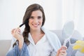 Delighted casual brown haired woman in white pajamas applying powder on her face