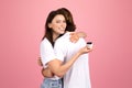 Delighted woman with a bright smile hugging a man while sneakily holding an engagement ring box behind his back Royalty Free Stock Photo