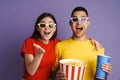 Delighted couple in 3d glasses eating popcorn while watching movie