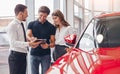 Delighted couple and manager signing papers in car dealership Royalty Free Stock Photo