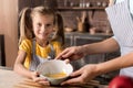 Delighted daughter holding the bowl with her mother