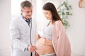 Delighted doctor using stethoscope while checking patient