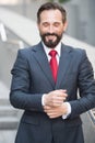 Delighted entrepreneur keeping his eyes closed while touching his shirt sleeves