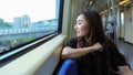Delighted ethnic female sitting on passenger seat and riding modern train while looking out of window with fun, active and happy. Royalty Free Stock Photo