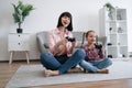 Parent and daughter playing video game with joypads on floor