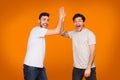 Delighted Friends Giving High Five Gesture, Orange Background