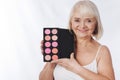 Delighted good looking woman holding a rouge palette