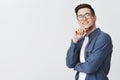 Delighted happy and satisfied handsome young male student in glasses and blue shirt holding hand on chin and smiling Royalty Free Stock Photo