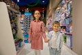 Delighted little children walk among display cases with toys in store