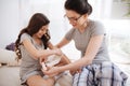Delighted mother bandaging elbow of her little daughter at home