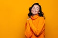 Delighted positive brunette woman smiling, wear high neck knitted orange sweater, has good mood, dreamily closed her eyes, Royalty Free Stock Photo