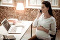 Delighted professional pregnant businesswoman answering the call