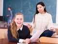 Delighted schoolgirl and Chinese girl schoolmate reading notification Royalty Free Stock Photo