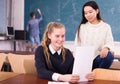 Delighted schoolgirl and Chinese girl schoolmate reading notification