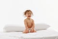 Delighted toddler, little girl with wet hair in diaper smiling while seated on soft bedspread against white studio Royalty Free Stock Photo
