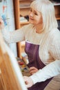 Delighted woman painting on a canvas