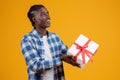 Delighted young black man holding white gift box with red ribbon Royalty Free Stock Photo