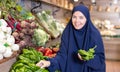 Delighted young Muslim woman purchaser choosing pepper in grocery store Royalty Free Stock Photo