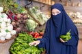 Delighted young Muslim woman purchaser choosing pepper in grocery store Royalty Free Stock Photo