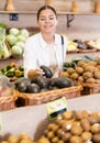 Delighted young woman purchaser choosing apples in grocery store