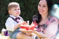 delightful baby boy, accompanied by his mother, birthday celebration cake with 1 candle.