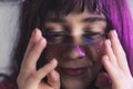 delightful Caucasian girl with purple hair holding a half disk horizontally near her eyes, closeup shot