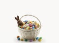 A white basket with full of multicolor candies, jelly beans, bunny chocolate, easter eggs around, Easter holiday, generative AI Royalty Free Stock Photo