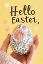 Hand holding a floral-decorated Easter egg with cheerful yellow background Royalty Free Stock Photo