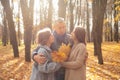 Delightful family of mother, father, daughter having fun together, embracing, collect leaves and relax in golden woods Royalty Free Stock Photo