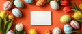 A delightful flat lay features an empty square card surrounded by an array of small Easter eggs and blooming spring