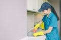 Delightful girl in cap and uniform stands and works at sink. She smiles a bit. Girl is professional cleaner.