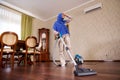 Delightful happy Arab Muslim young woman or housewife with vacuum cleaner, vacuuming the floor at home, dancing, singing, enjoying Royalty Free Stock Photo