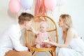 Delightful happy, festive full family of man and woman care about child feeding father by present cake sitting on chair