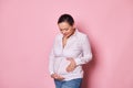 Delightful happy pregnant woman, smiling cutely while touching and caressing her belly, enjoying her carefree pregnancy Royalty Free Stock Photo