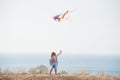 Delightful small free active boy laughing holding flying color kite near blue sea shore and sky in summer leisure Royalty Free Stock Photo