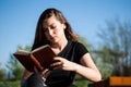 Tranquil Reader: A Young Woman Immersed in Vintage Literature at a Serene Park Bench