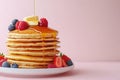 Delightful stack of pancakes with syrup, berries, and butter on blue plate against festive background Royalty Free Stock Photo