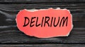 DELIRIUM - word on a red torn piece of paper on a dark wooden background