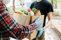 Delivering food to senior citizens in quarantine during Covid-19 Coronavirus epidemic. Courier in black shirt medical gloves