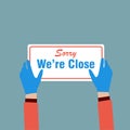Hands holding `Sorry We`re Close` ,sign label on the door store is closing earlier for social distancing in covid-19