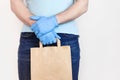 Delivery against Coronavirus 2019-nCov in pandemic Contactless delivery. Male hand in blue medical gloves holds craft paper bag on