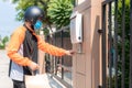 Delivery Asian man wear protective mask in orange uniform and ready to send delivering Food bag in front of customer houes with