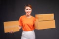 Delivery asian woman or courier wearing an orange uniform holds a cardboard box in studio