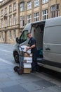 Delivery being loaded onto trolley from van by man male worker in the street