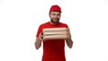 Delivery boy in a red uniform holding a stack of pizza boxes making a home delivery as seen through a spyhole. Shot with