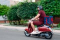 Delivery boy wearing red uniform on scooter with isothermal food case box driving fast. Express food delivery service