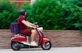 Delivery boy wearing red uniform on scooter with isothermal food case box driving fast. Express food delivery service