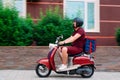 Delivery boy wearing red uniform on scooter with isothermal food case box driving fast. Express food delivery service